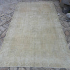 Beige 6' x 10' vintage Turkish distressed rug in wool and cotton, shown on the floor.