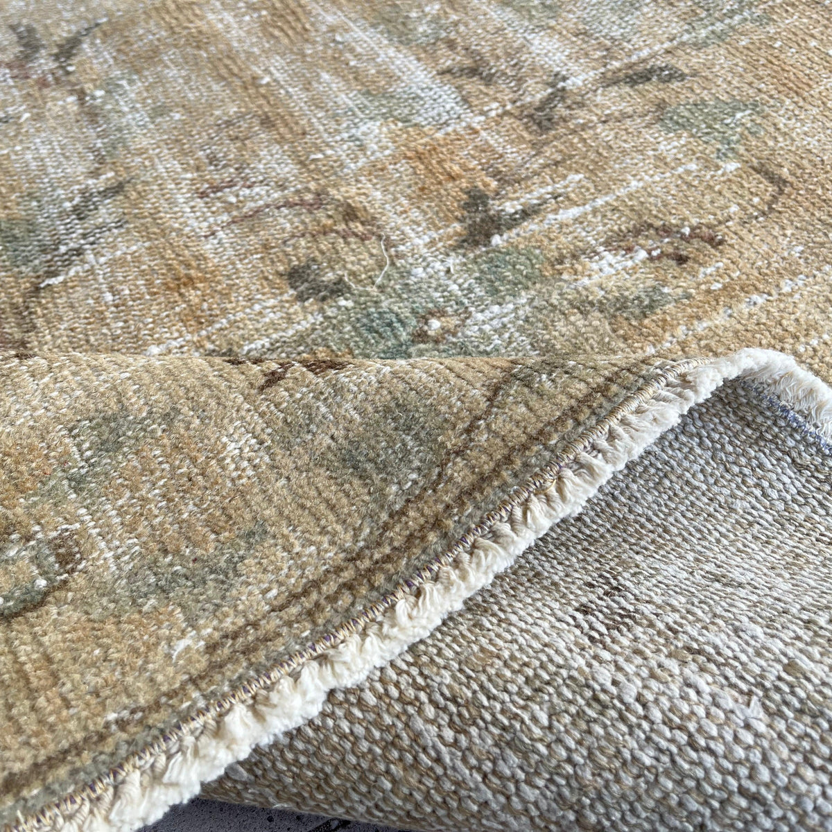 Close-up of the beige vintage Turkish distressed rug showing medallion details, hand-knotted weave, wool and cotton and low pile.