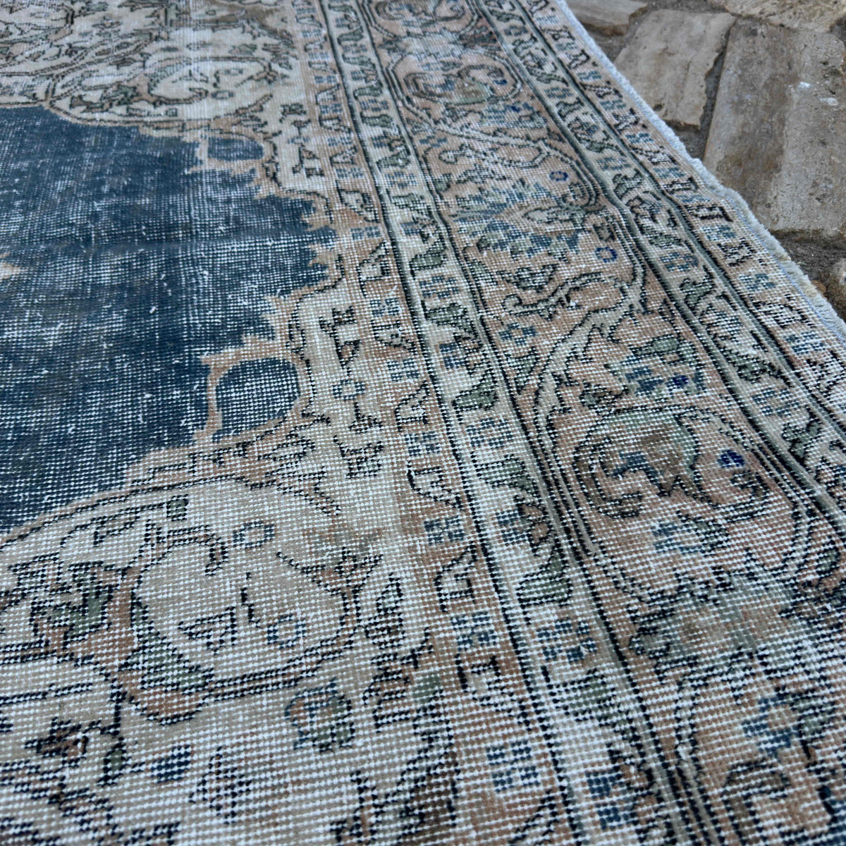 Close-up of the blue vintage Turkish distressed rug showing medallion details, hand-knotted weave, wool and cotton and low pile.