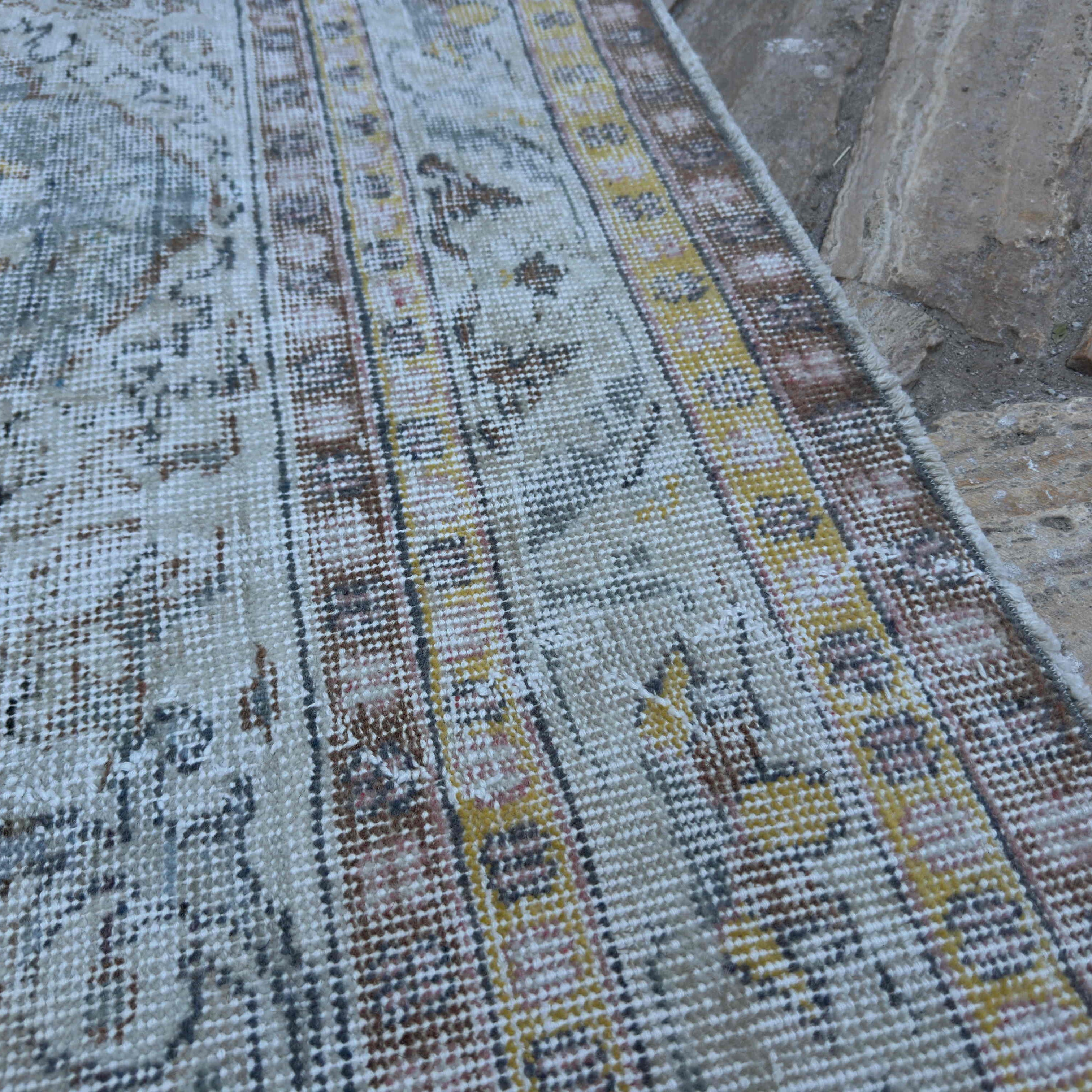 Close-up of the blue vintage Turkish distressed rug showing neutral details, hand-knotted weave, wool and cotton and low pile.