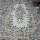 Pink 6' x 10' vintage Turkish distressed rug in wool and cotton, shown on the floor.
