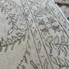 Close-up of the beige vintage Turkish distressed rug showing neutral details, hand-knotted weave, wool and cotton and low pile.