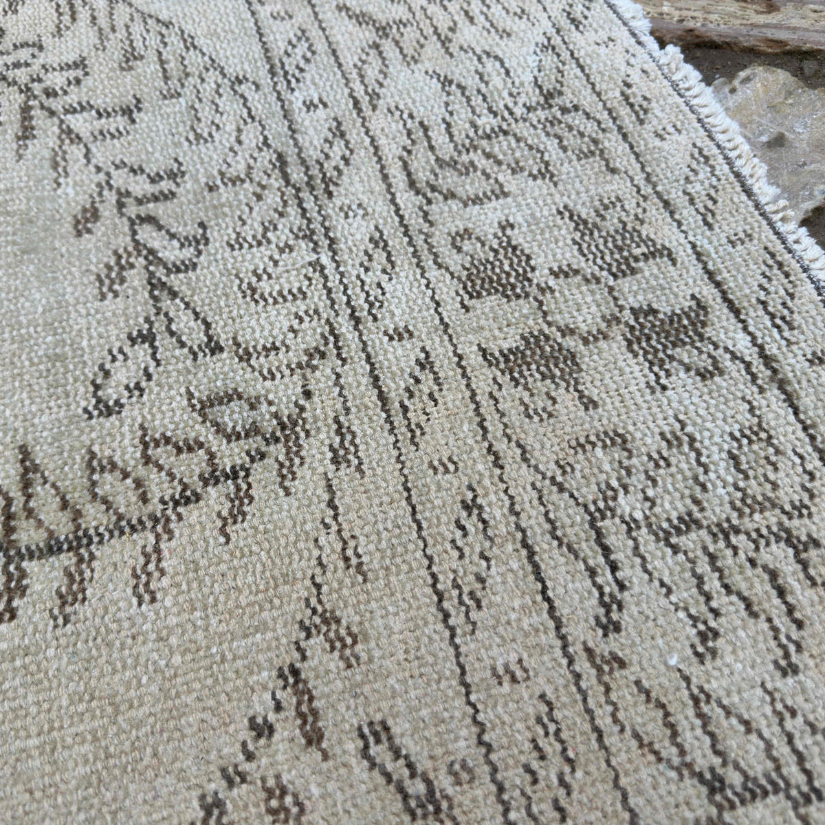 Close-up of the beige vintage Turkish distressed rug showing neutral details, hand-knotted weave, wool and cotton and low pile.