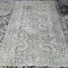 Beige 6' x 9' vintage Turkish distressed rug in wool and cotton, shown on the floor.