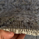 Close-up of the black vintage Turkish distressed rug showing overdyed details, hand-knotted weave, wool and cotton and low pile.