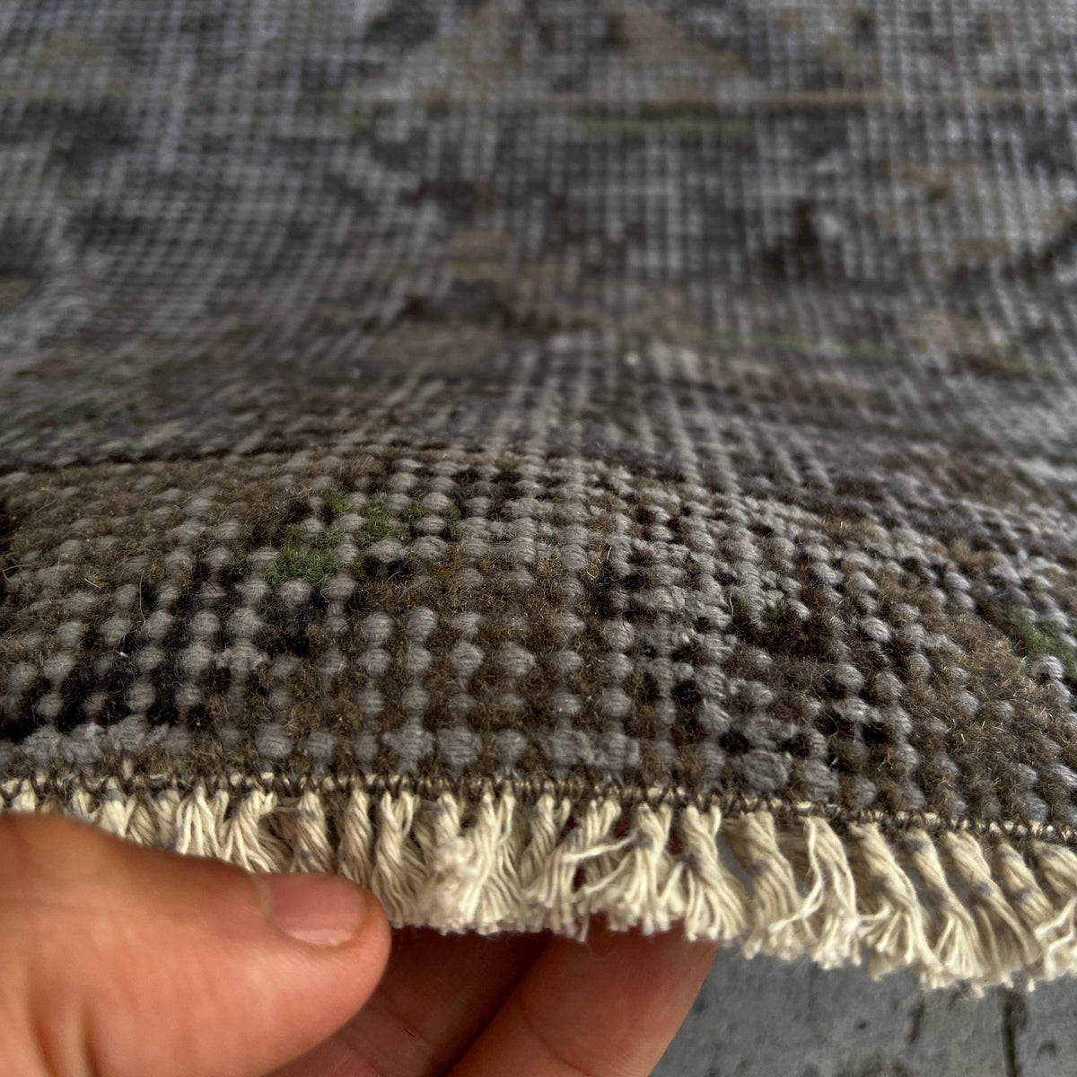 Close-up of the black vintage Turkish distressed rug showing overdyed details, hand-knotted weave, wool and cotton and low pile.