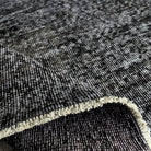 Close-up of the black vintage Turkish distressed rug showing overdyed details, hand-knotted weave, wool and cotton and low pile.