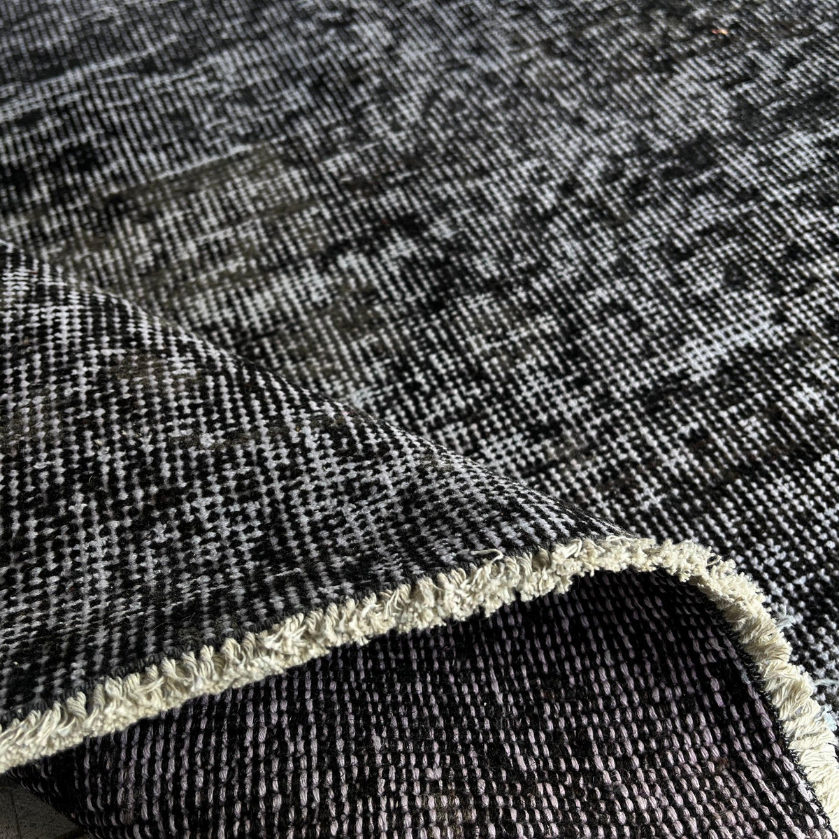 Close-up of the black vintage Turkish distressed rug showing overdyed details, hand-knotted weave, wool and cotton and low pile.