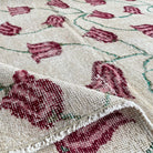 Close-up of the beige vintage Turkish distressed rug showing floral details, hand-knotted weave, wool and cotton and low pile.