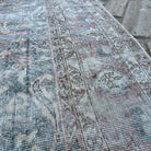 Close-up of the pale green vintage Turkish distressed rug showing traditional details, hand-knotted weave, wool and cotton and low pile.