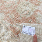 Close-up of the pale pink vintage Turkish distressed rug showing floral details, hand-knotted weave, wool and cotton and low pile.
