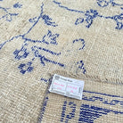 Close-up of the blue vintage Turkish distressed rug showing medallion details, hand-knotted weave, wool and cotton and low pile.
