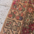 1970s red vintage Turkish distressed runner rug with traditional design, hand-knotted weave and low pile.