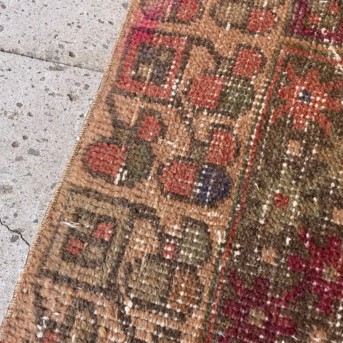 1970s red vintage Turkish distressed runner rug with traditional design, hand-knotted weave and low pile.