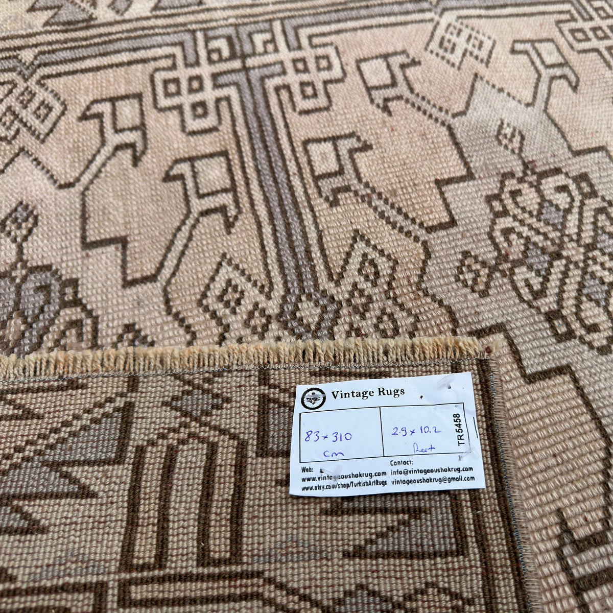 Close-up of the beige vintage Turkish distressed runner rug showing traditional details, hand-knotted weave, wool and cotton and low pile.
