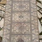1970s beige vintage Turkish distressed runner rug with traditional design, hand-knotted weave and low pile.