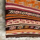 Close-up of the orange vintage Turkish flatweave rug showing striped details, flatweave construction, wool and cotton and low pile.