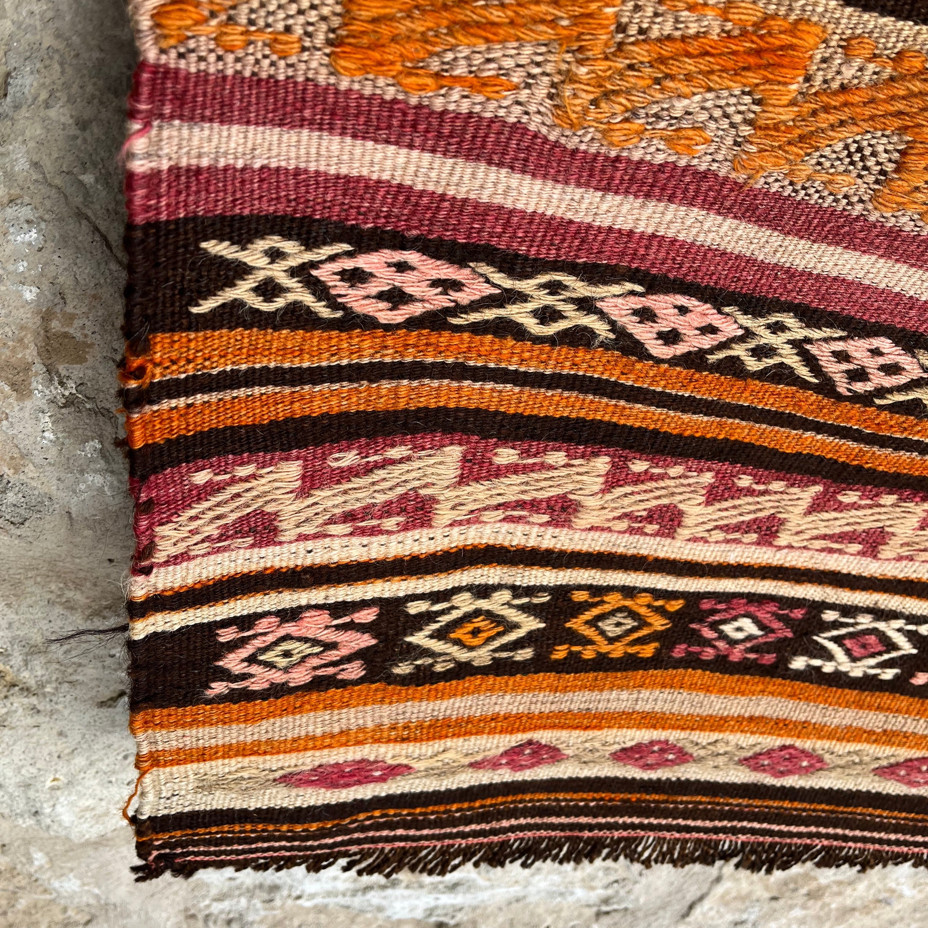 Close-up of the orange vintage Turkish flatweave rug showing striped details, flatweave construction, wool and cotton and low pile.