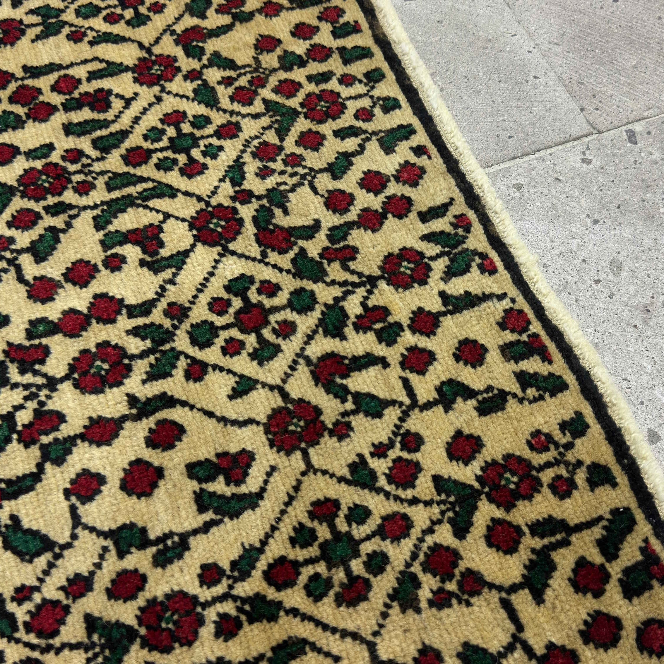 Close-up of the red vintage Turkish floral rug showing floral details, hand-knotted weave, wool and cotton and low pile.