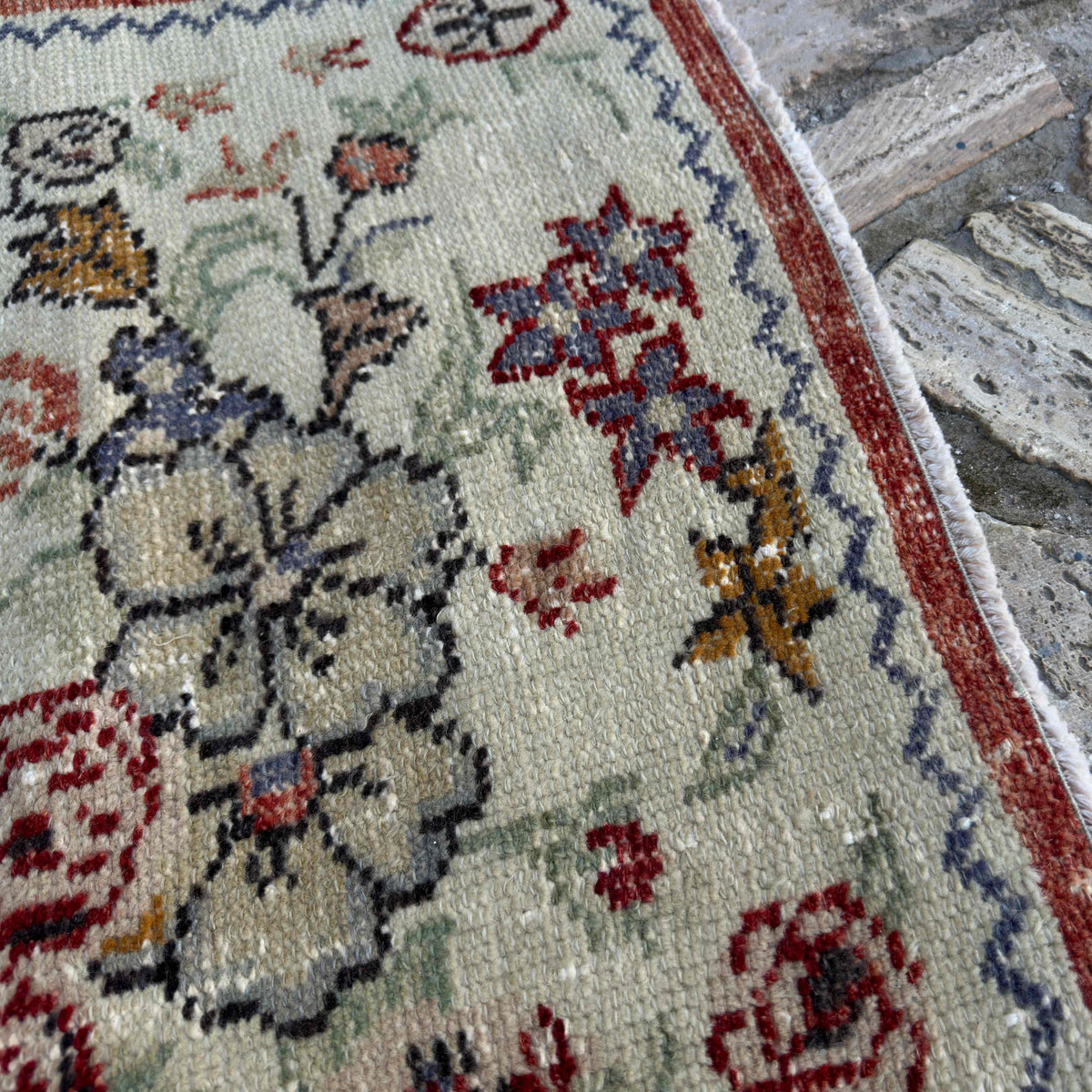 Close-up of the red vintage Turkish floral rug showing floral details, hand-knotted weave, wool and cotton and low pile.