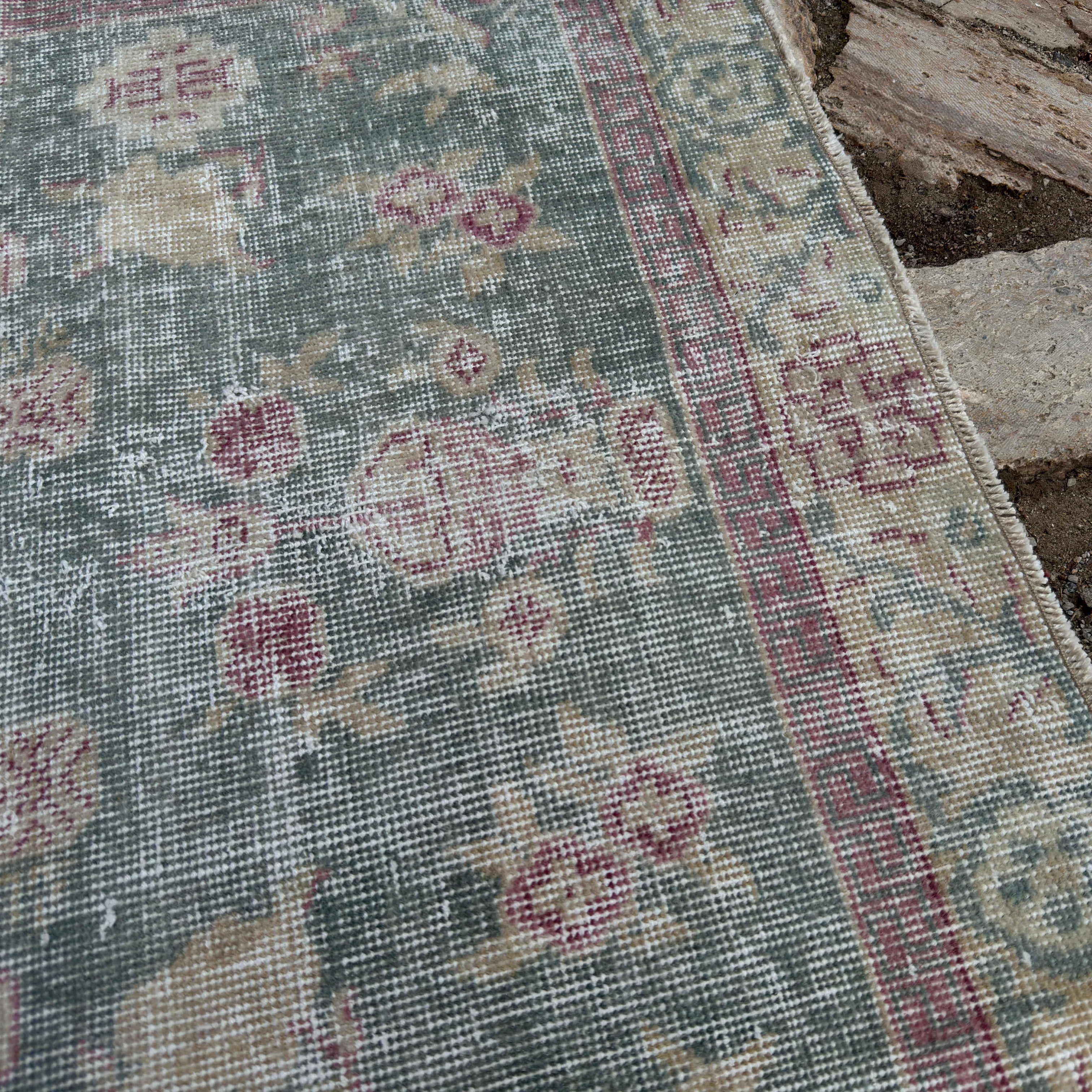 Close-up of the pale blue vintage Turkish floral rug showing floral details, hand-knotted weave, wool and cotton and low pile.