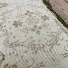 Close-up of the beige vintage Turkish floral rug showing geometric details, hand-knotted weave, wool and cotton and low pile.
