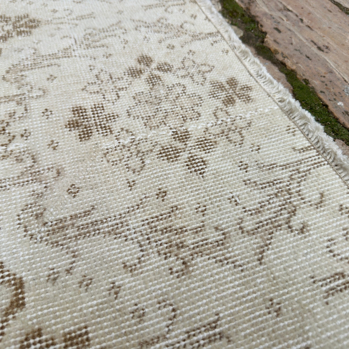 Close-up of the beige vintage Turkish floral rug showing geometric details, hand-knotted weave, wool and cotton and low pile.