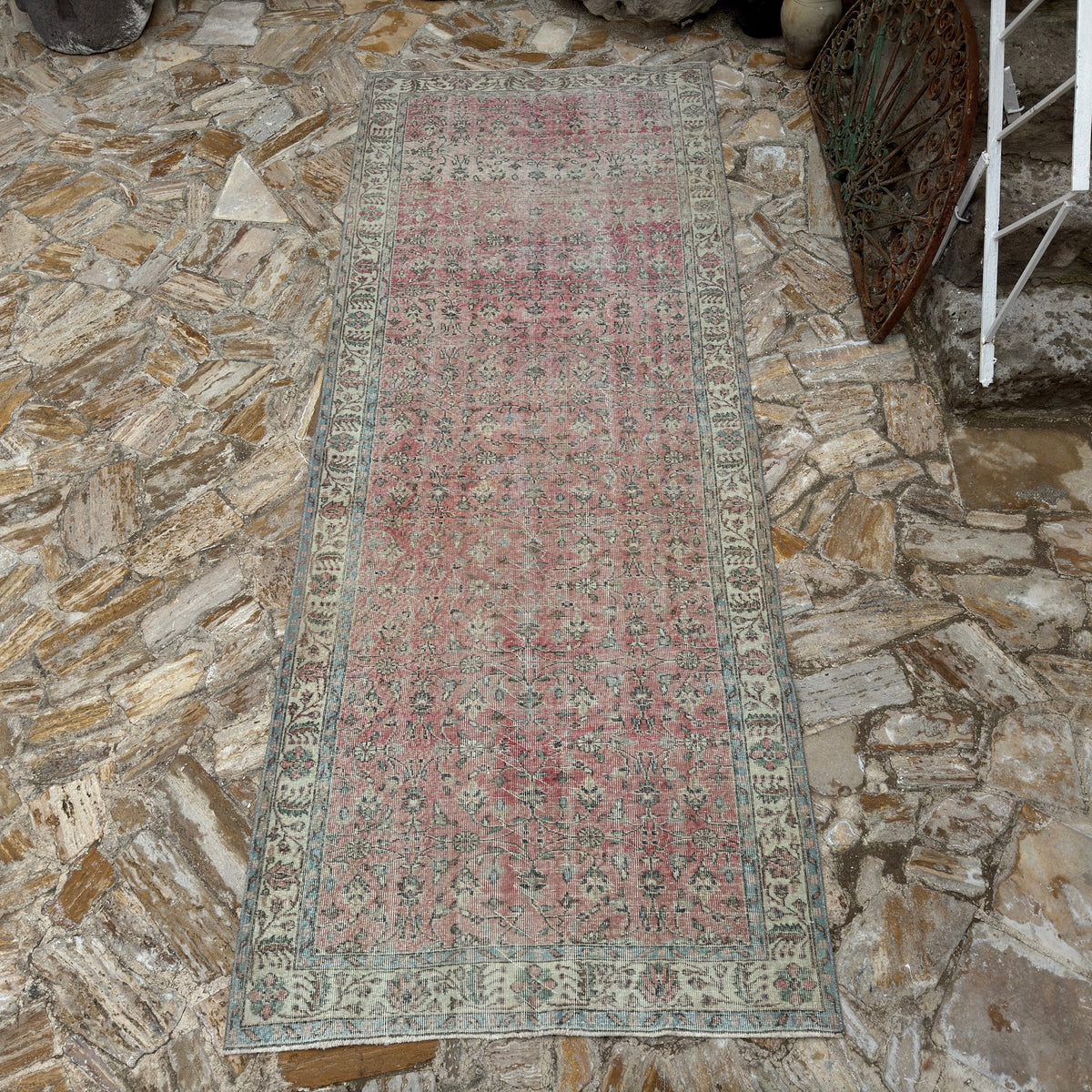Pink 5' x 12' vintage Turkish floral rug in wool and cotton, shown on the floor.