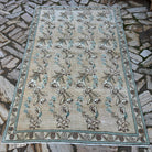 Beige 5' x 7' vintage Turkish floral rug in wool and cotton, shown on the floor.