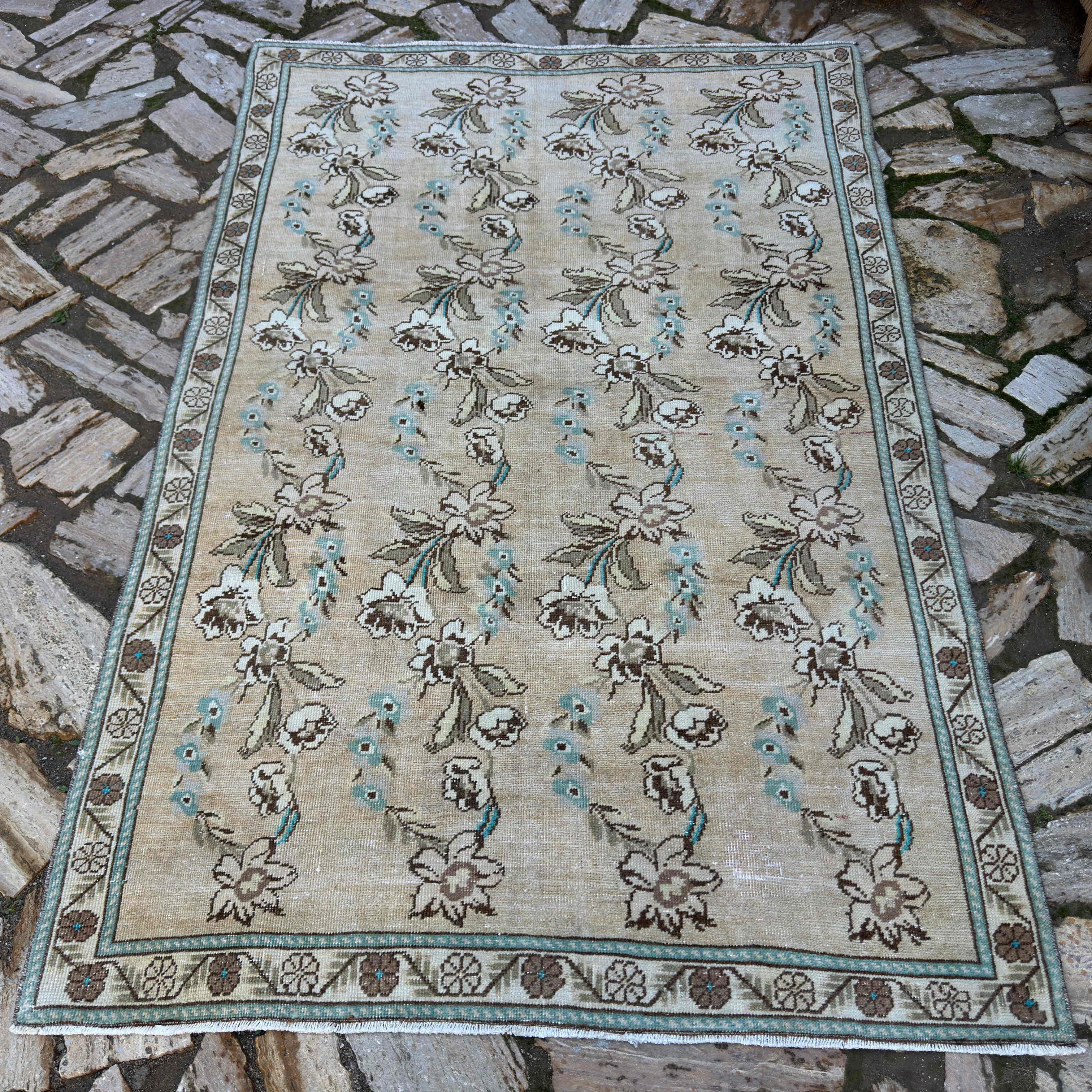 Beige 5' x 7' vintage Turkish floral rug in wool and cotton, shown on the floor.