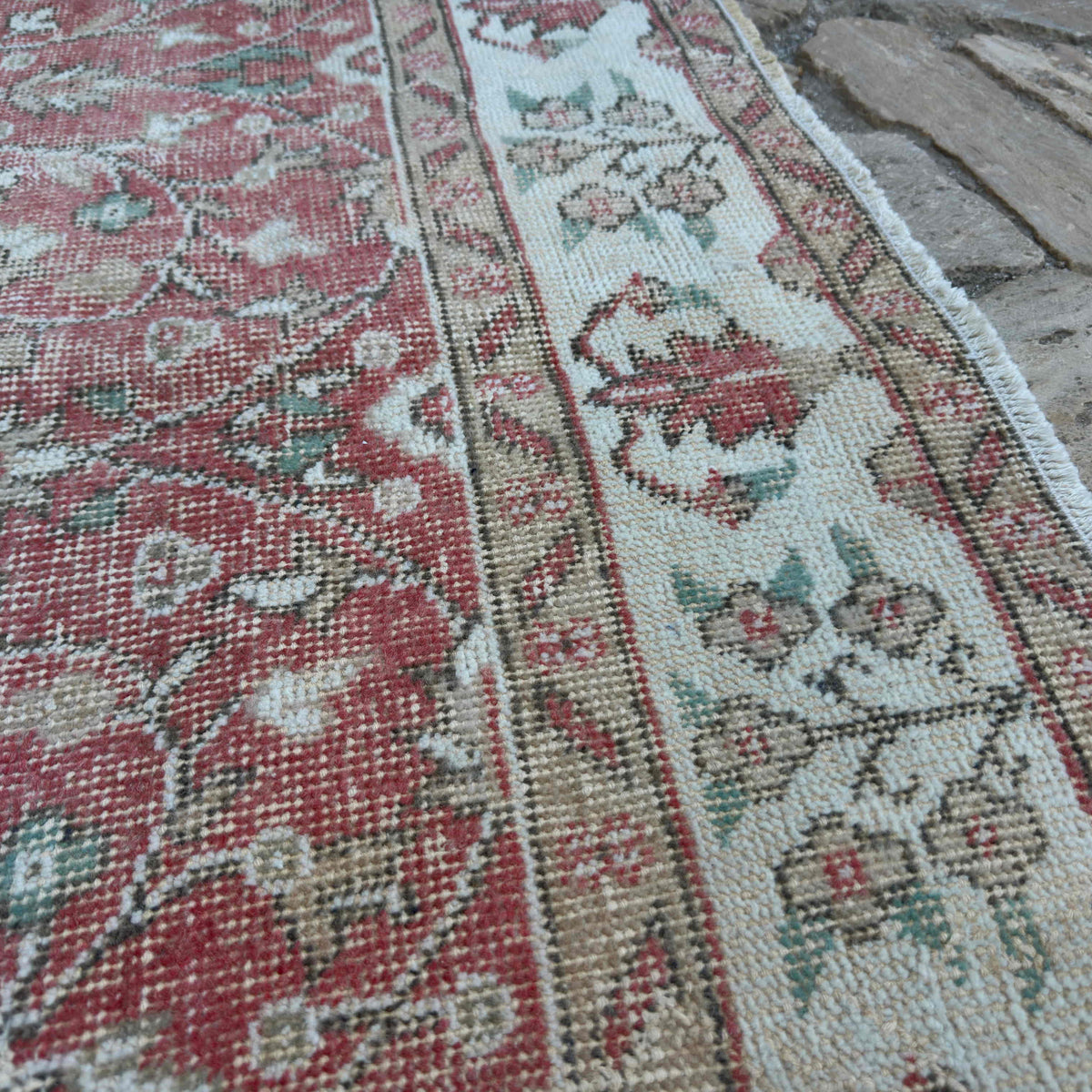 Close-up of the pink vintage Turkish floral rug showing floral details, hand-knotted weave, wool and cotton and low pile.