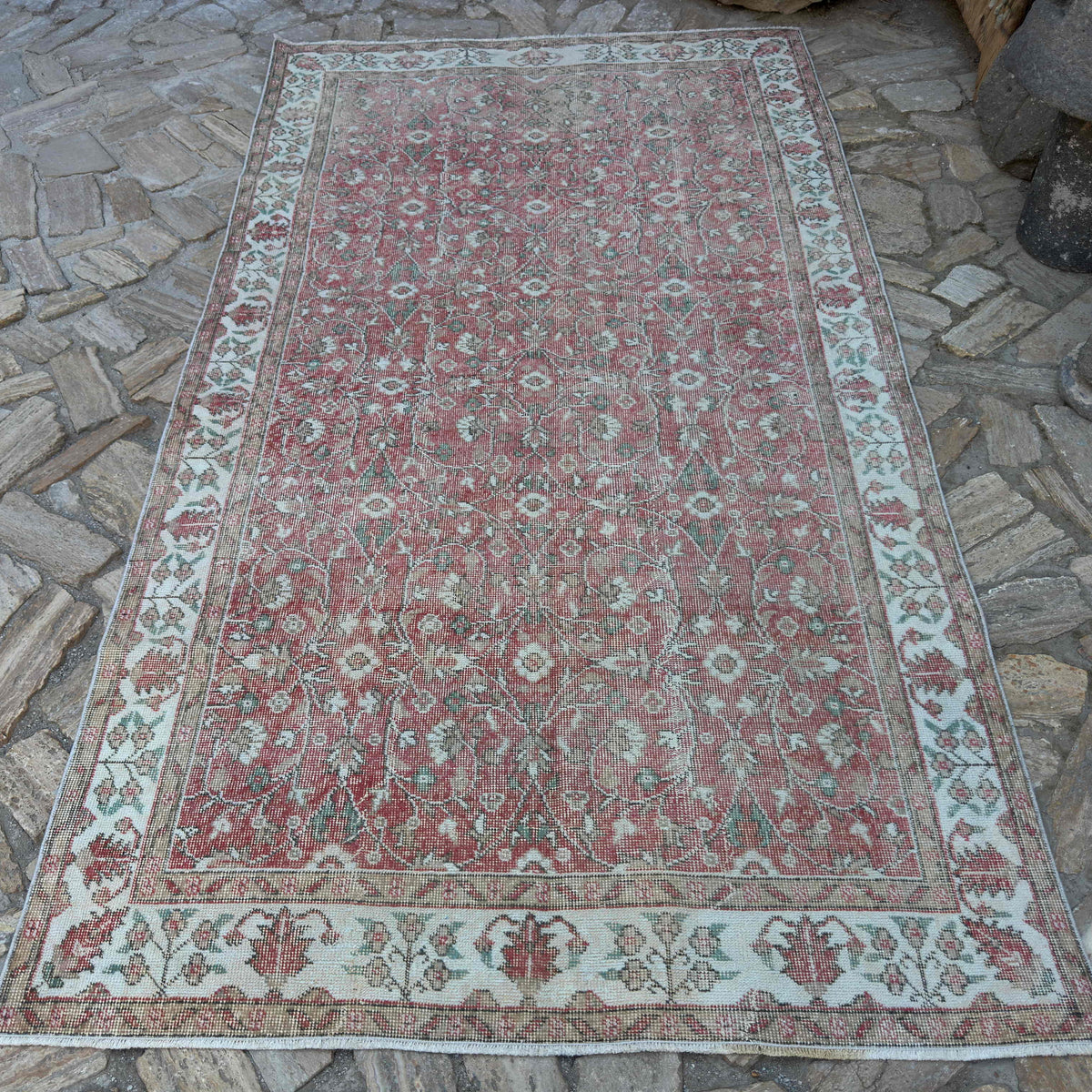 Pink 5' x 9' vintage Turkish floral rug in wool and cotton, shown on the floor.