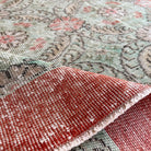 Close-up of the pale green vintage Turkish floral rug showing floral details, hand-knotted weave, wool and cotton and low pile.