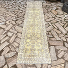 Yellow 2' x 10' vintage Turkish floral runner rug in wool and cotton, shown on the floor.