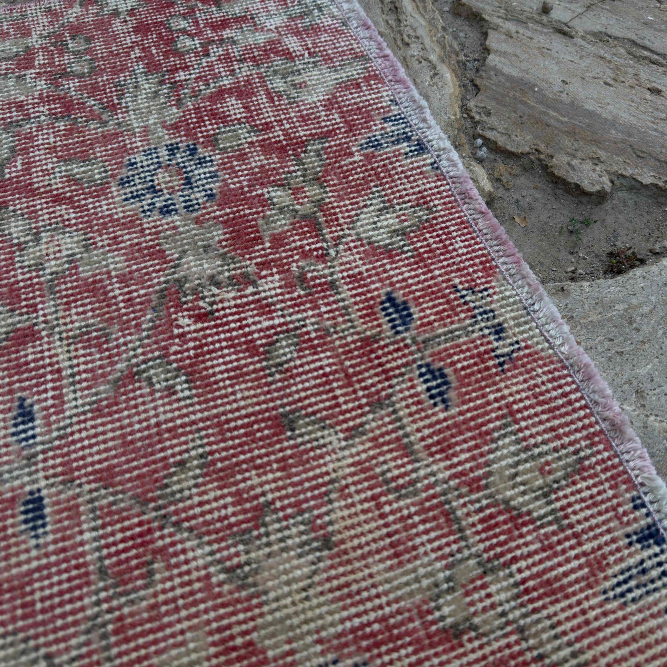 Close-up of the pale red vintage Turkish floral runner rug showing floral details, hand-knotted weave, wool and cotton and low pile.