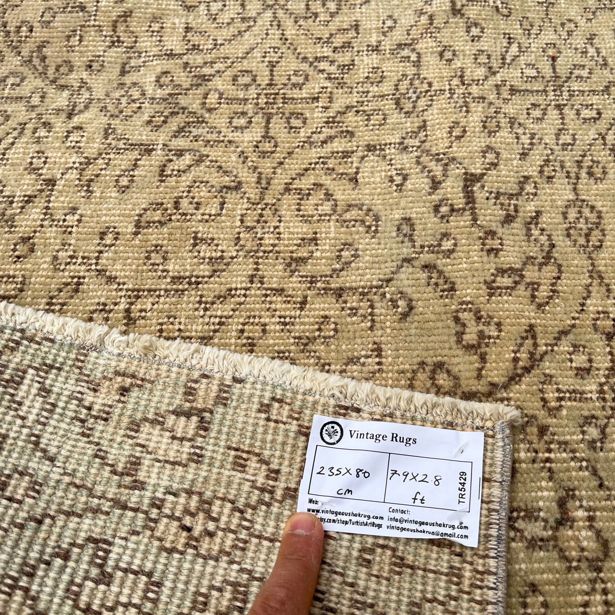 Close-up of the beige vintage Turkish floral runner rug showing floral details, hand-knotted weave, wool and cotton and low pile.