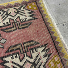 Close-up of the pink vintage Turkish geometric carpet showing traditional details, hand-knotted weave, wool and cotton and low pile.