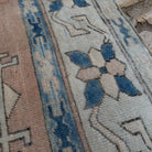 Close-up of the pale blue vintage Turkish geometric carpet showing medallion details, hand-knotted weave, wool and cotton and low pile.