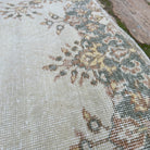 Close-up of the pale green vintage Turkish geometric rug showing medallion details, hand-knotted weave, wool and cotton and low pile.