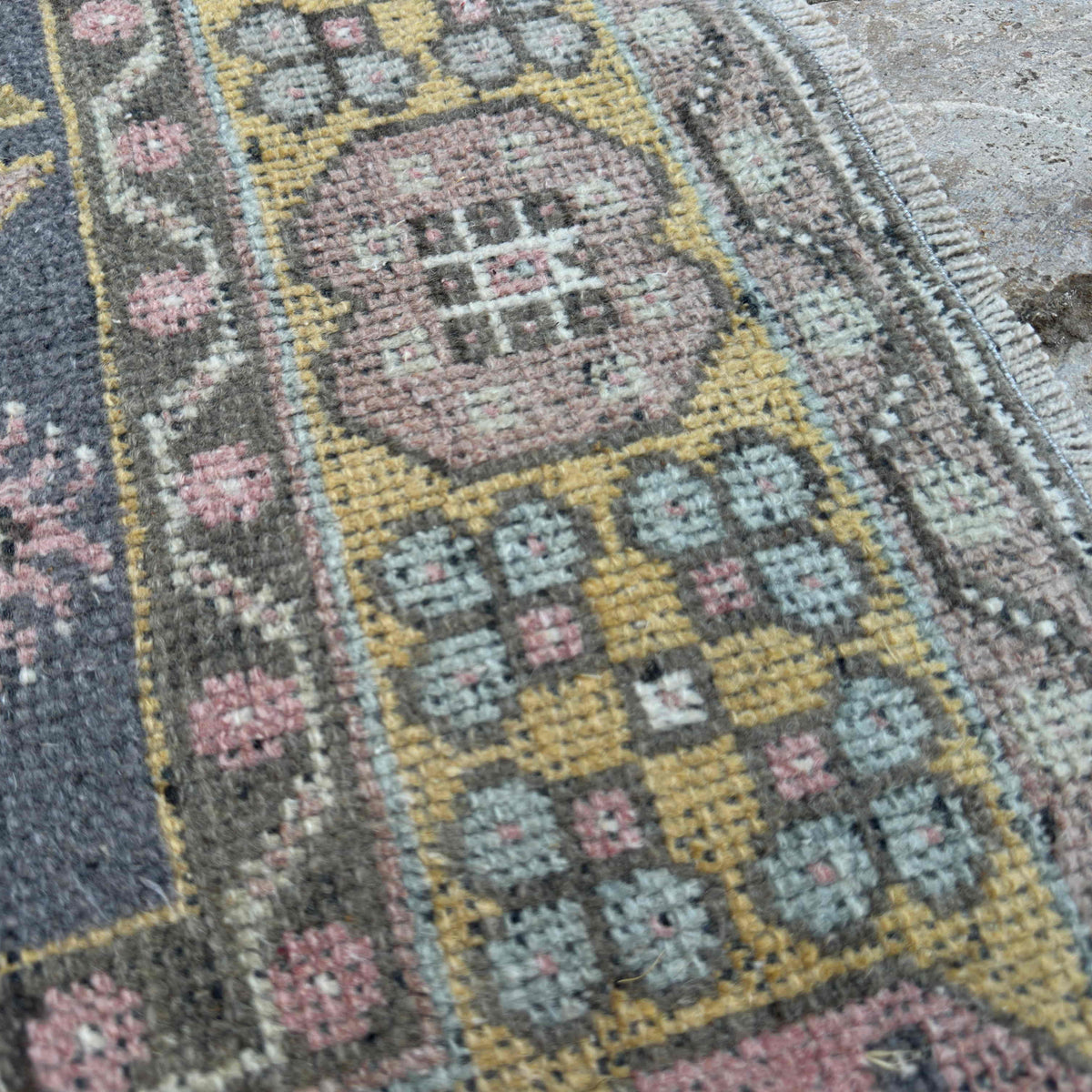 Close-up of the pink vintage Turkish geometric rug showing traditional details, hand-knotted weave, wool and cotton and low pile.