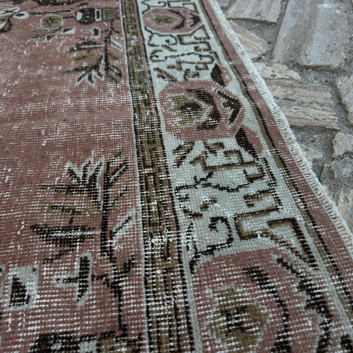 Close-up of the pink vintage Turkish geometric rug showing geometric details, hand-knotted weave, wool and cotton and low pile.