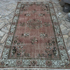 Pink 5' x 9' vintage Turkish geometric rug in wool and cotton, shown on the floor.