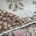 Close-up of the pink vintage Turkish geometric rug showing medallion details, hand-knotted weave, wool and cotton and low pile.