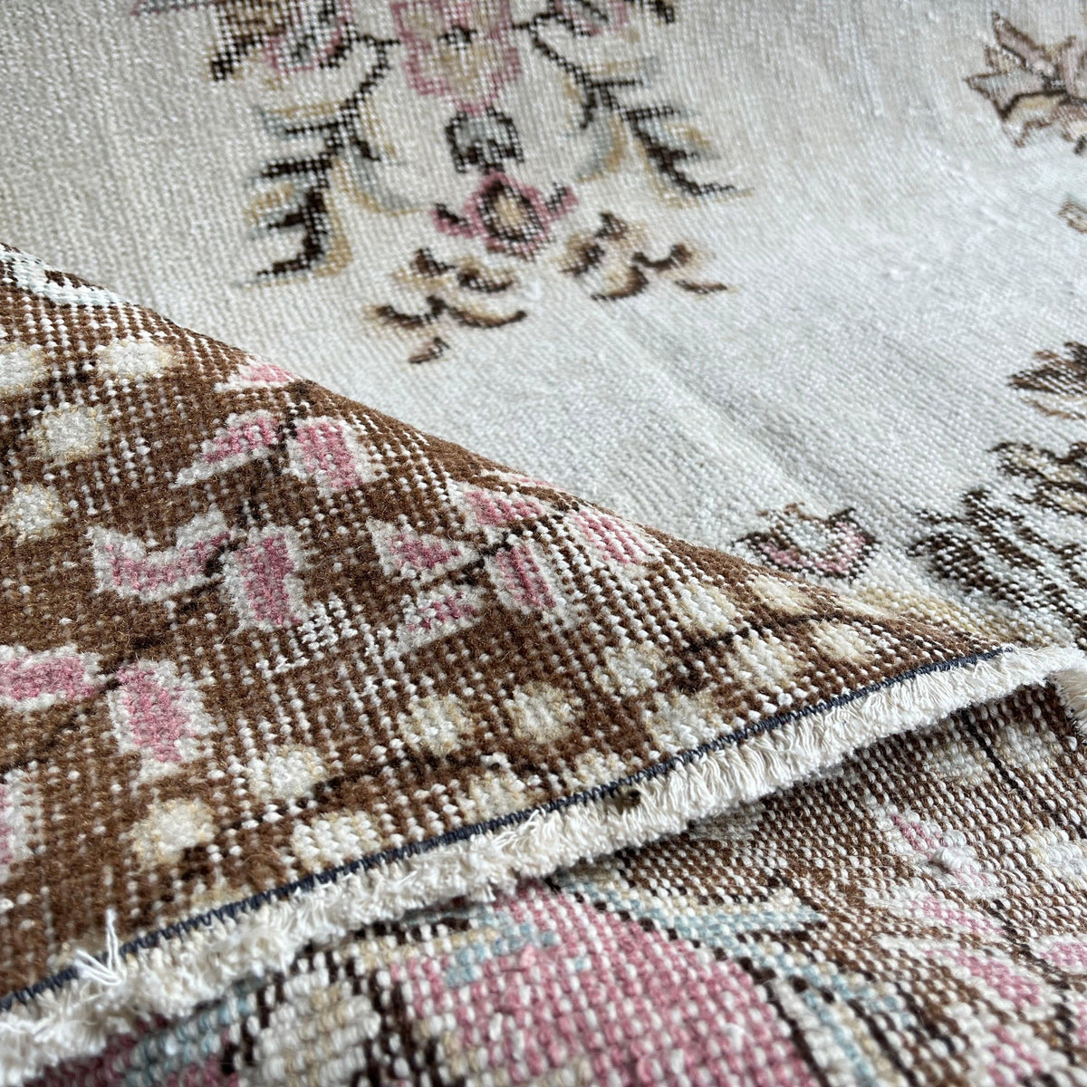 Close-up of the pink vintage Turkish geometric rug showing medallion details, hand-knotted weave, wool and cotton and low pile.