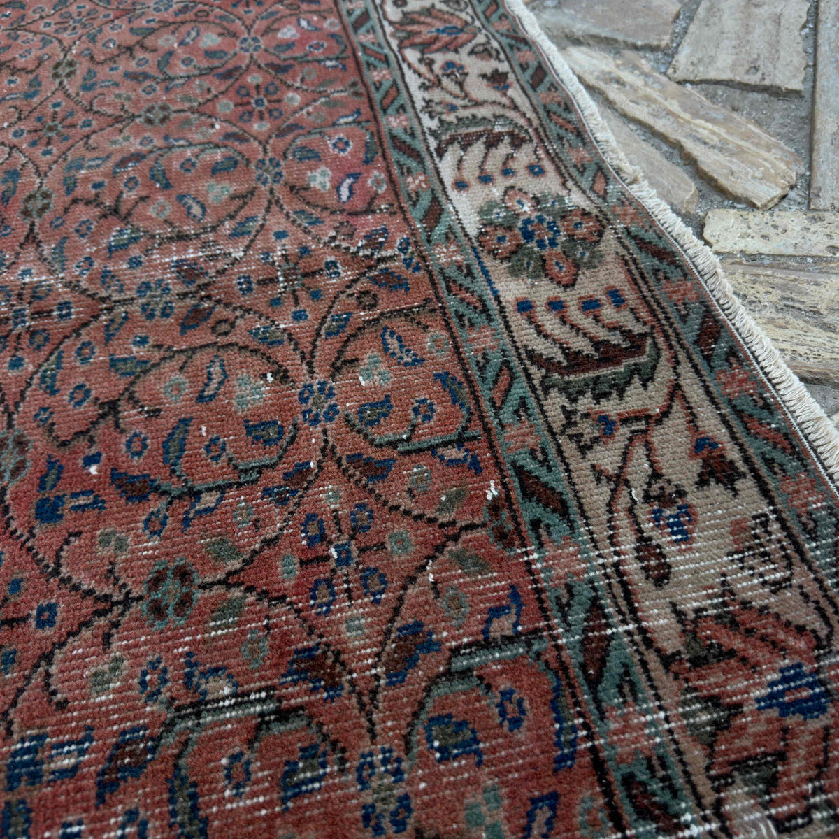 Close-up of the red vintage Turkish geometric rug showing floral details, hand-knotted weave, wool and cotton and low pile.