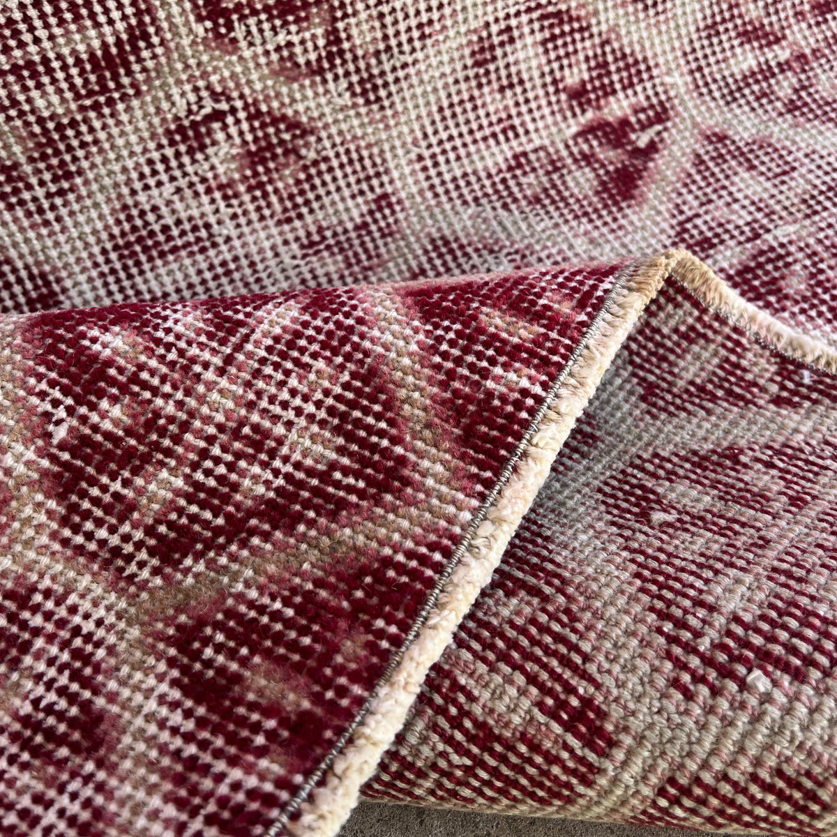 Close-up of the red vintage Turkish geometric rug showing floral details, hand-knotted weave, wool and cotton and low pile.