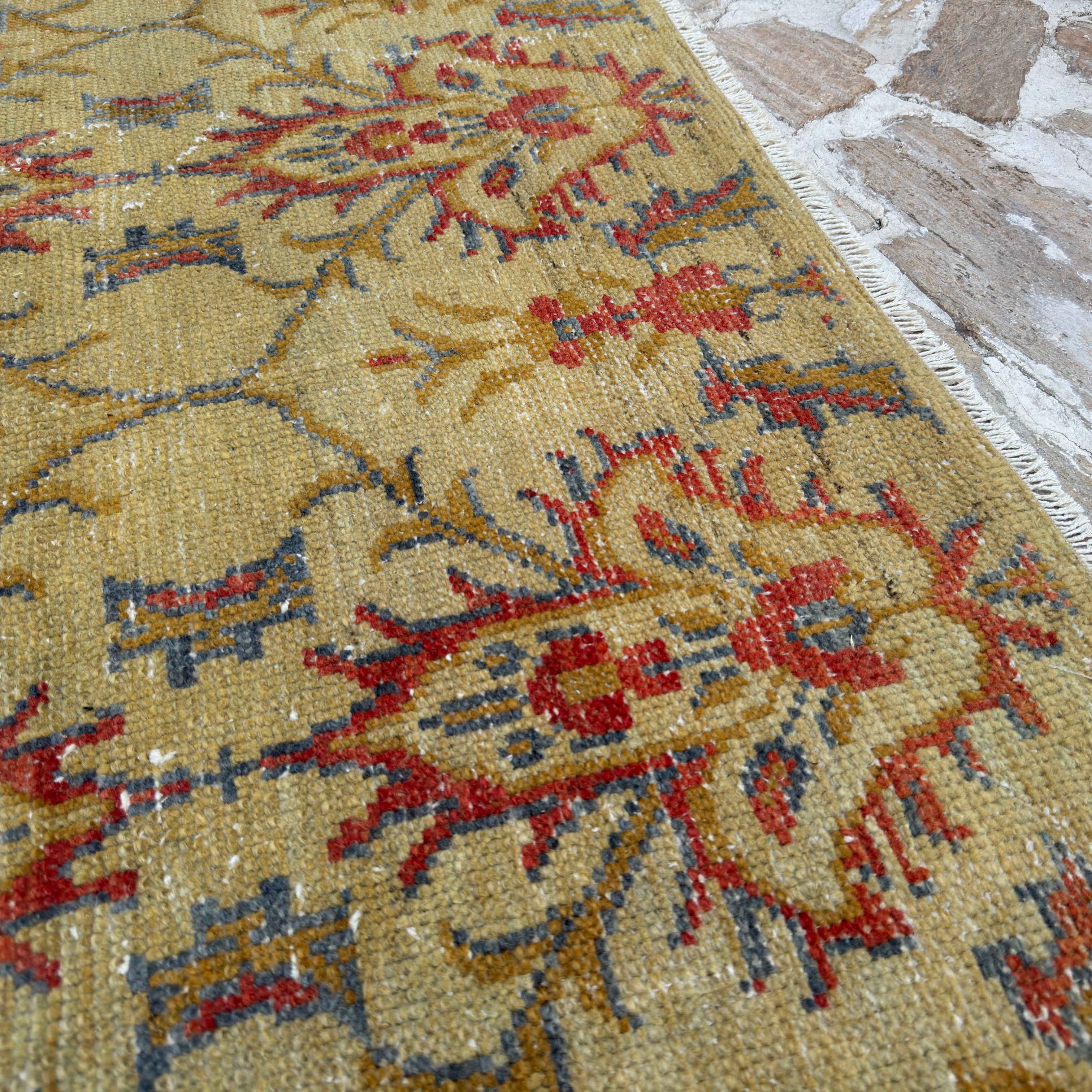 Close-up of the yellow vintage Turkish geometric rug showing floral details, hand-knotted weave, wool and cotton and low pile.