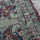 Close-up of the green vintage Turkish geometric rug showing medallion details, hand-knotted weave, wool and cotton and low pile.