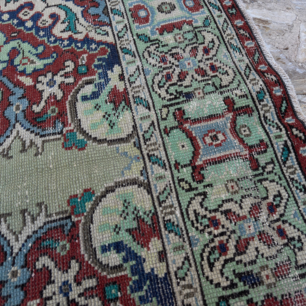 Close-up of the green vintage Turkish geometric rug showing medallion details, hand-knotted weave, wool and cotton and low pile.
