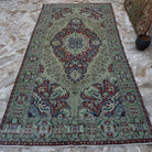 Green 6' x 11' vintage Turkish geometric rug in wool and cotton, shown on the floor.